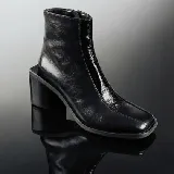 Bota corta de cuero vacuno color negro, con diseño de punta cuadrada y taco bloque de madera. Presenta un acabado brillante en la parte frontal y cierre lateral interno.