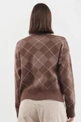 Cardigan de punto con escote en V y cierre frontal de botones. Presenta un diseño de estampado argyle en tonos marrones con líneas blancas. Posee mangas largas con puños acanalados y ruedo también acanalado.
