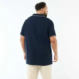 Remera de piqué de algodón color azul marino, con cuello polo sin botones y detalle de línea blanca en el borde del cuello y las mangas.
