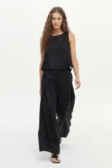 Pantalón de lino color beige, de pierna amplia, con elástico en la cintura, pinzas en el frente y bolsillos laterales y traseros.