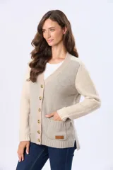 Saco tipo cardigan de tejido grueso con diseño de bloques de color en beige, rosado y blanco. Cuenta con botones frontales y dos bolsillos delanteros.