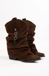 Botas texanas de cuero gamuzado color marrón, con caña alta arrugada y detalle de argollas metálicas.