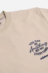 Remera manga larga de textura acanalada en color beige, con cuello redondo y estampa tipográfica frontal en color azul marino.