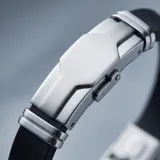 Pulsera masculina con diseño moderno que combina eslabones de acero inoxidable con una banda central de goma negra. Cuenta con un cierre de seguridad integrado.