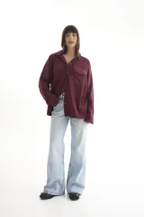 Camisa negra de pana, corte oversize, con cuello camisero, cierre frontal con botones, dos bolsillos con solapa en el pecho y mangas largas con puños abotonados.