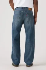 Jeans de corte holgado y tiro medio, con diseño clásico de cinco bolsillos y cierre de botones. Presentan un lavado azul medio con efecto desgastado en los muslos.