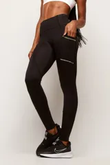 Calza deportiva de tiro alto confeccionada en poliamida de alta performance. Presenta bolsillos laterales con costuras en color contrastante y detalle de logo estampado en la pierna.