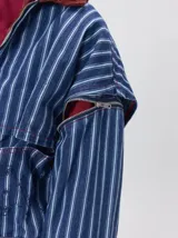 Campera de denim a rayas verticales con cuello de pana en color bordó. Presenta cierre frontal, mangas desmontables con cierre en los hombros, canesú en el pecho y bolsillos de parche cuadrados.