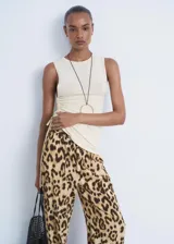 Pantalon de tiro medio con diseño recto y fluido, confeccionado en viscosa con estampado animal print de leopardo. Cuenta con cintura elástica con lazo de ajuste, forro interior y bolsillos laterales.