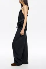 Pantalón de corte amplio y silueta relajada, color gris oscuro, con cintura elástica y cordón ajustable.