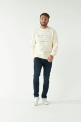 Buzo color crema de felpa con logo estampado en el frente, corte regular, cuello redondo, mangas largas con puños.