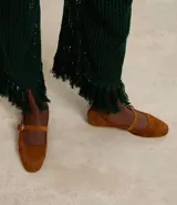 Zapatilla chatita femenina en gamuza color marrón, con punta redonda y tira con hebilla lateral.