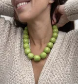 Collar de diseño artesanal compuesto por múltiples hileras de cuentas de resina pulida en una paleta de colores vibrantes que incluye tonos marrones, grises, verdes, naranjas y bordó.