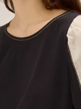 Blusa de diseño combinado con cuerpo delantero y espalda de algodón negro, y mangas abullonadas tres cuartos de lino en color beige con puños elásticos negros.