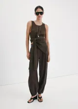 Pantalón balloon de tiro medio color marrón oscuro, con diseño de pinzas, trabillas y bolsillos laterales. Cuenta con cierre de gancho y cremallera.