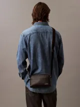 Bandolera negra Calvin Klein Jeans con correa ajustable, cierre de cremallera y logo de la marca en el frente.