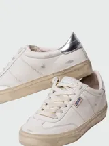 Championes Golden Goose modelo Soul Star, de cuero blanco con detalles en plateado en el talón y logo GGDB en el lateral. Diseño acordonado y suela con efecto envejecido.