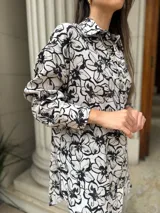 Camisa blanca con estampado floral negro, de corte amplio y mangas largas.