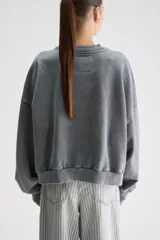 Buzo oversize gris de algodón con efecto acid wash, cuello redondo, hombros caídos, mangas largas y terminaciones acanaladas.