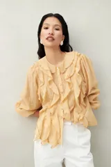 Camisa blanca de tencel liviana con cuello babero, volados románticos y manga larga. De caída suave y textura aireada.