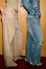 Jeans de corte boyfriend y tiro medio, con diseño de cinco bolsillos, cierre frontal con cremallera y botón metálico. Presenta un acabado lavado con detalles de roturas y desgastes.