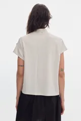 Blusa de jersey shiny color off-white, de manga corta, con cuello alto y calce holgado.