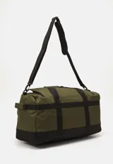 Bolso tipo duffle Carhartt, color marrón con base y detalles en negro. Cuenta con asas de mano y correa ajustable para hombro. Presenta un bolsillo frontal con solapa y el logo cuadrado de la marca.
