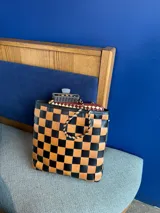 Bolso tipo tote de cuero trenzado a mano con diseño de damero en colores marrón y beige. Cuenta con doble asa trenzada y forro interior.