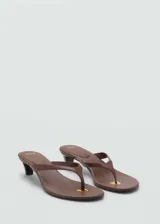 Sandalia tipo flip-flop con tacón kitten de 4 cm, diseño destalonado y puntera abierta. Presenta un detalle metálico en la base y acabado en tono marrón.