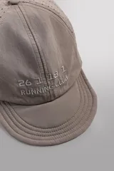 Gorra deportiva de tejido técnico ligero en color azul marino, con visera corta y paneles laterales perforados para mayor ventilación. Presenta logos bordados a tono en el frente.