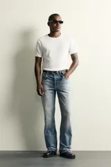 Jeans flare fit de denim de algodón en color celeste con lavado efecto desgastado. Presentan diseño de cinco bolsillos, tiro medio, cierre frontal con cremallera y botón, y bajo con acabado irregular.