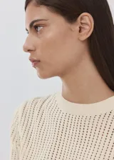 Chaleco de punto fino calado color beige, con cuello redondo y mangas cortas.