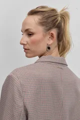 Blazer de corte sastrero con diseño cruzado y cierre de doble botonadura frontal. Presenta solapas clásicas y bolsillos laterales con solapa, confeccionado en tela con estampado de cuadros pequeños.