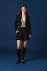 Saco tipo spencer negro de corte corto y estructurado, con solapas clásicas y detalles de pines decorativos distribuidos en la parte frontal.