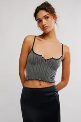 Top crop de tejido acanalado y texturado gris, con escote redondo amplio, tiras finas, botonadura frontal estilo henley con ribetes negros y terminación con ruedo en lechuga.