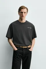 Camiseta de corte boxy fit, color negro, con cuello redondo y manga corta. Presenta estampados a contraste en el pecho y en la espalda.
