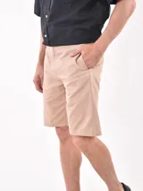 Bermuda de gabardina color beige, con corte recto, bolsillos laterales y cierre frontal.