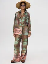 Camisa oversize de viscosa con diseño estampado abstracto en tonos tierra, verdes y rosados. Presenta cuello clásico, cierre frontal con botones y un bolsillo cuadrado en el pecho.