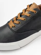 Champion de estilo urbano en color azul marino, con detalles en cuero sintético color suela en la lengüeta y el talón. Presenta perforaciones decorativas en los laterales y suela de goma blanca.
