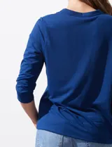 Blusa azul con cuello a la base y escote en V. Tiene bolsillos con cierre metálico.