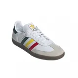 Championes adidas Samba OG de diseño clásico, con exterior de cuero blanco, puntera de gamuza gris y suela de goma color caramelo. Presenta las icónicas tres tiras laterales en colores verde, amarillo y rojo, con el nombre del modelo en dorado.