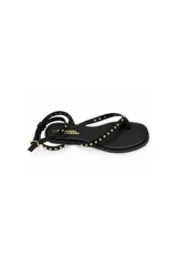 Sandalia plana Daniel Cassin de color negro, con diseño de tiras delgadas decoradas con tachas metálicas doradas, formato de dedo y pulsera ajustable al tobillo con hebilla.