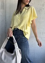 Camisa amarilla de mangas cortas con volados, cuello mao y botones frontales.