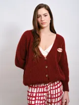 Cardigan marrón de punto grueso con cuello en V, cierre frontal con botones y parche bordado en el pecho.