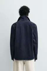 Cazadora de denim de algodón azul marino oscuro, corte regular fit, con cuello solapa, bolsillos frontales de plastrón y cierre de botonadura frontal.