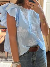 Camisa celeste con bordado de hojas blancas, mangas cortas con volados y corte holgado.