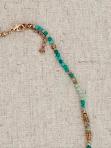 Collar de estilo boho con cuentas de piedra en tonos turquesa y verde, intercaladas con piezas metálicas doradas. Presenta dijes colgantes en forma de luna, estrella y una piedra rectangular.
