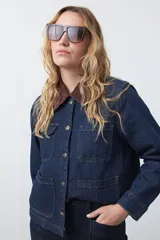 Campera de jean azul oscuro con cuello de pana en color marrón, cierre frontal con botones metálicos y bolsillos frontales tipo parche.