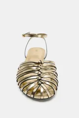 Sandalias planas tipo cangrejera en tono dorado metalizado, con múltiples tiras delanteras, tira ajustable en el tobillo con hebilla y suela baja.