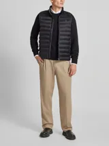 Chaleco acolchado negro Tommy Hilfiger, con cuello alto, cierre de cremallera, bolsillos laterales y logo bordado en el pecho.